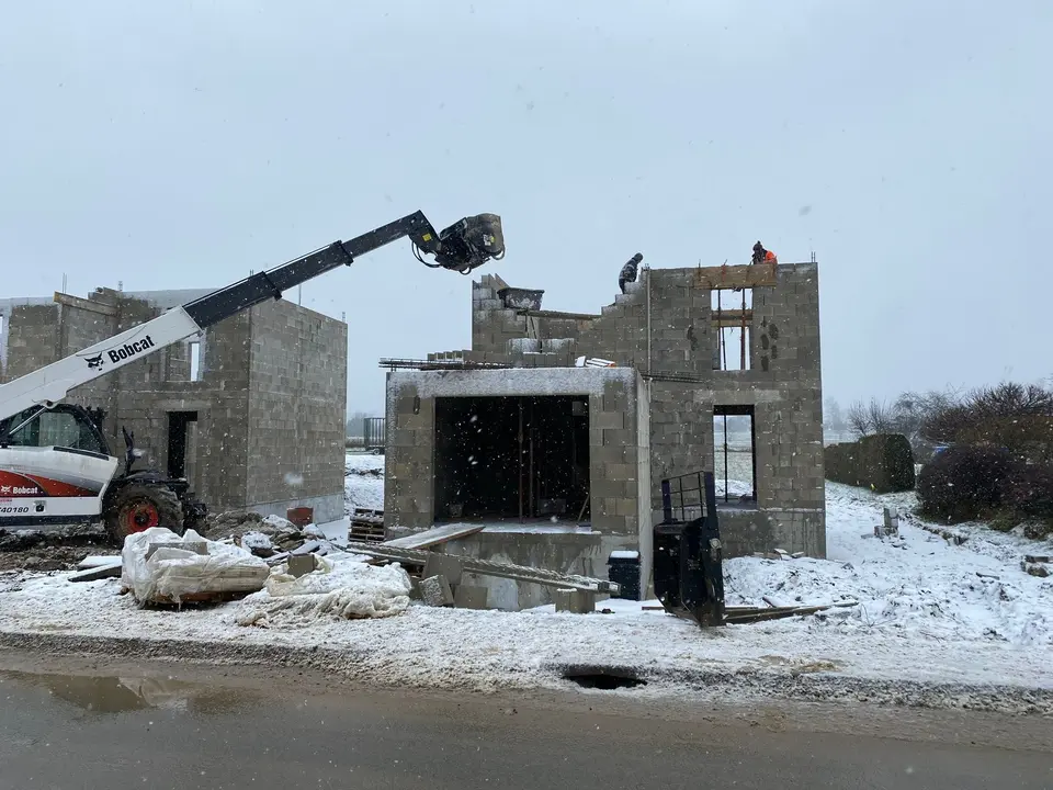 Chantier de maison en parpaing sous la neige, gros œuvre en hiver
