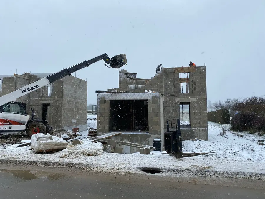 Chantier de maison en parpaing sous la neige, gros œuvre en hiver