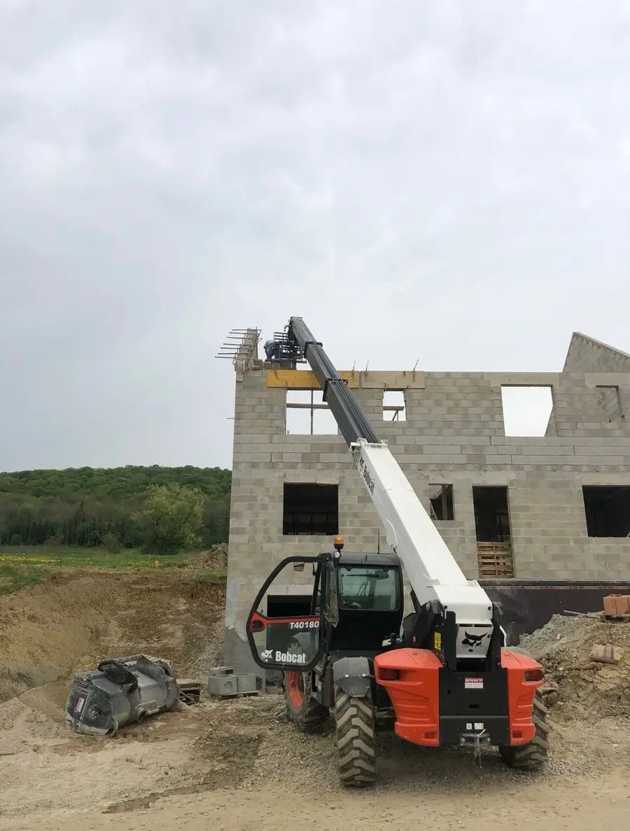 Élévation des murs en parpaing d’une maison à étage avec chariot télescopique
