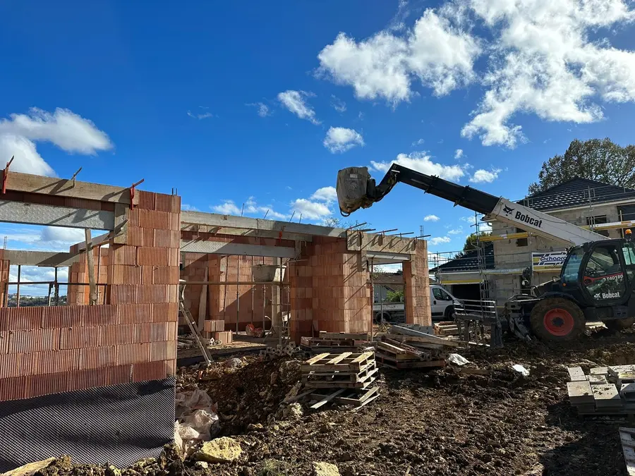 Murs en brique d’une maison en cours de construction, chariot télescopique en action