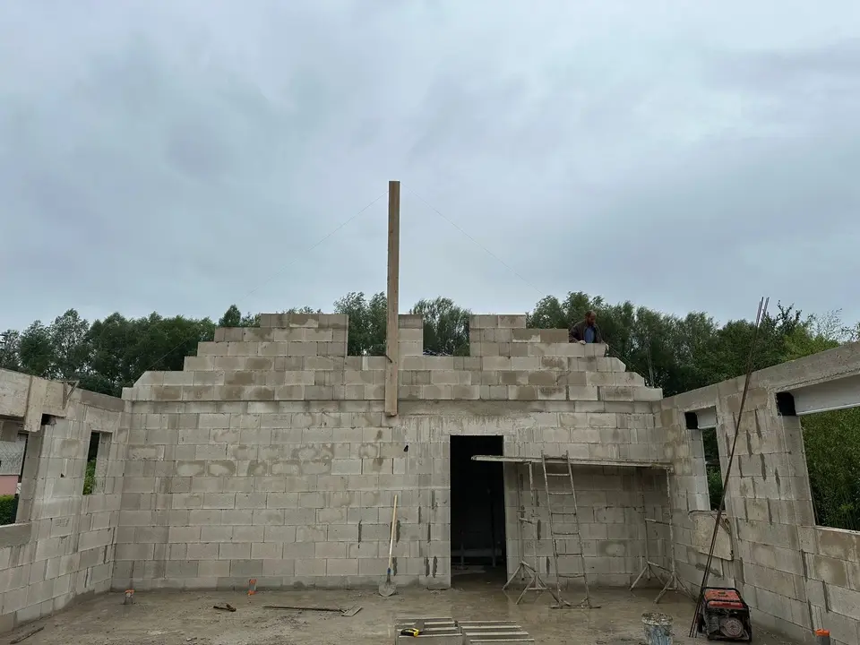 Maison en parpaing aux pignons élevés, vue depuis l’intérieur du chantier