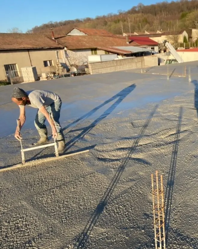 Maçon tirant une dalle béton à la règle sur un chantier BASAK BTP