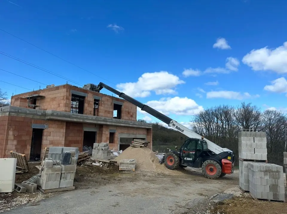 Construction d’une villa R+1 en brique avec engin de terrassement sur le chantier